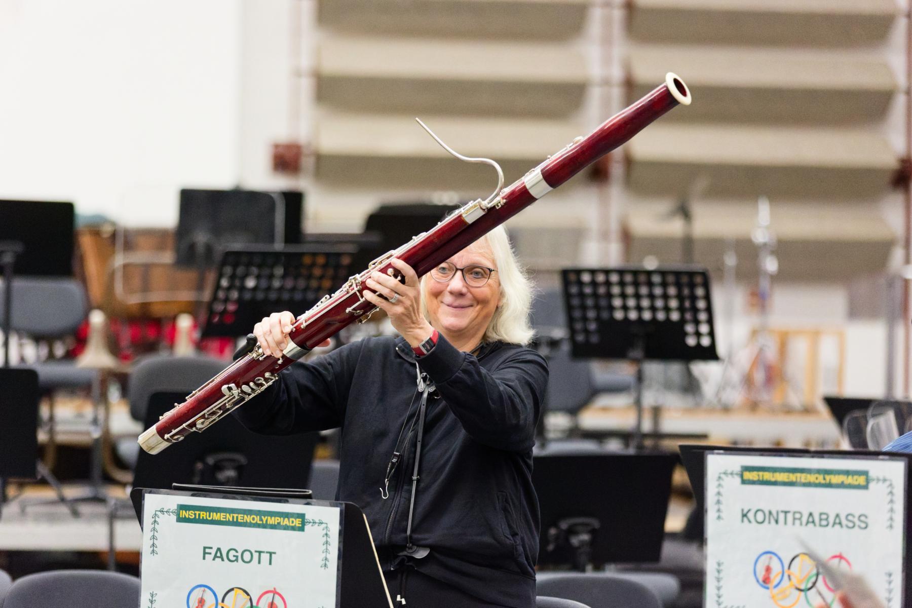 Eine Frau hält ein Musikinstrument hoch.
