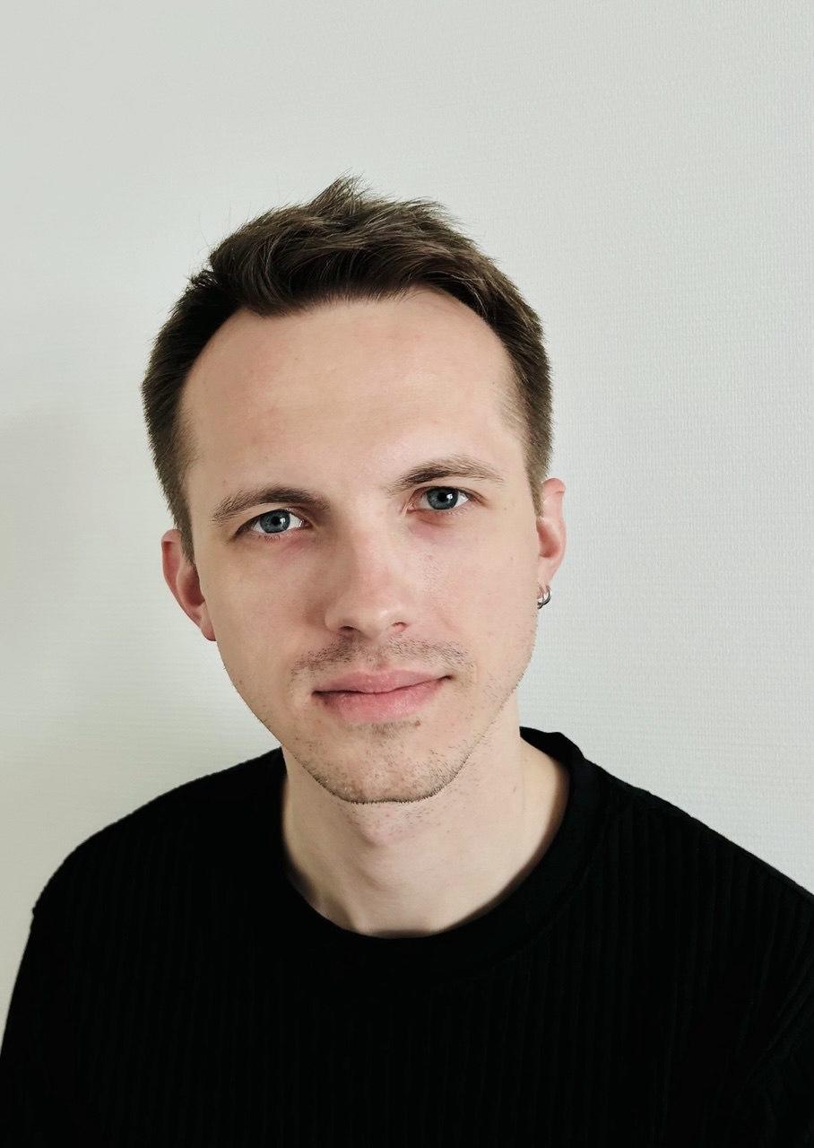 Portrait eines Mannes vor hellem Hintergrund. Er hat kurze dunkle Haare, einen Dreitage-Bart und trägt einen dunklen Pullover. Er schaut geradeaus und freundlich in die Kamera.