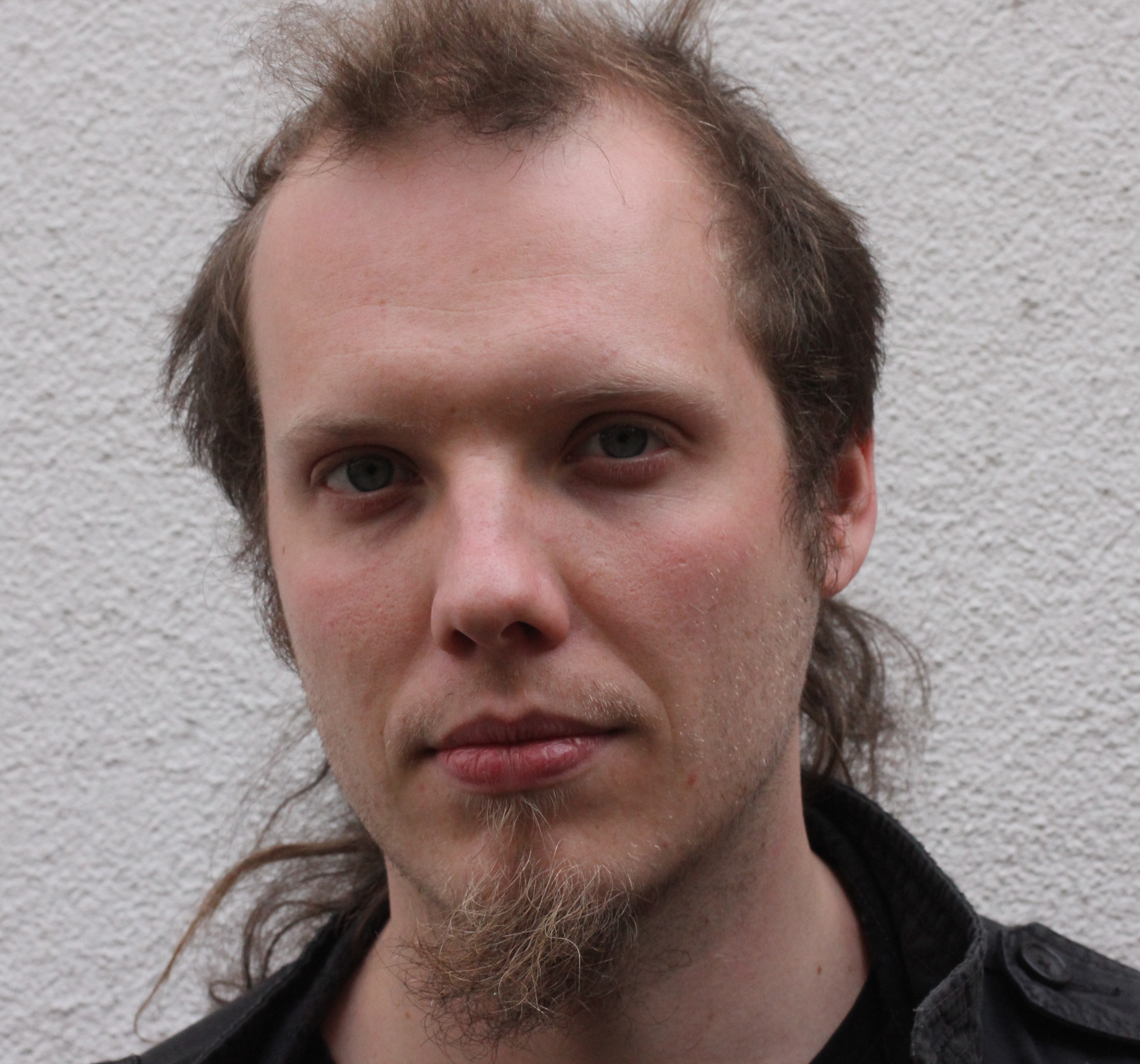 Ein junger Mann schaut ernst in die Kamera.