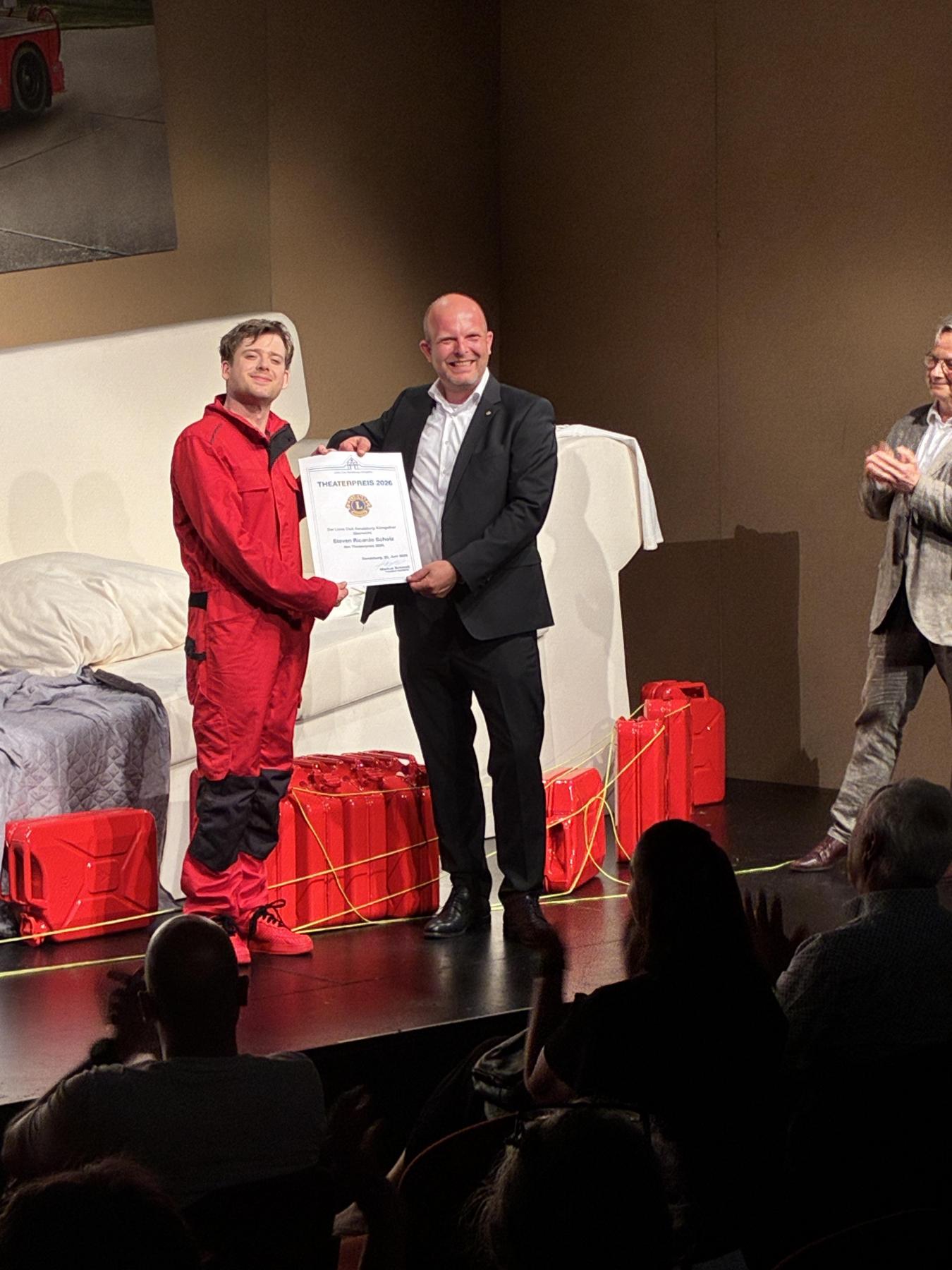 Lions-Präsident Markus Schmidt übergibt den Theaterpreis an den Schauspieler Steven Ricardo Scholz, auf der Bühne