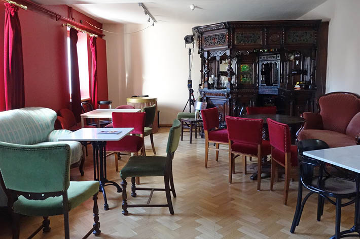 Ein Bild des Kleinen Foyers, verschiedene Tische und Stühle sind an den Wänden des Raumes verteilt