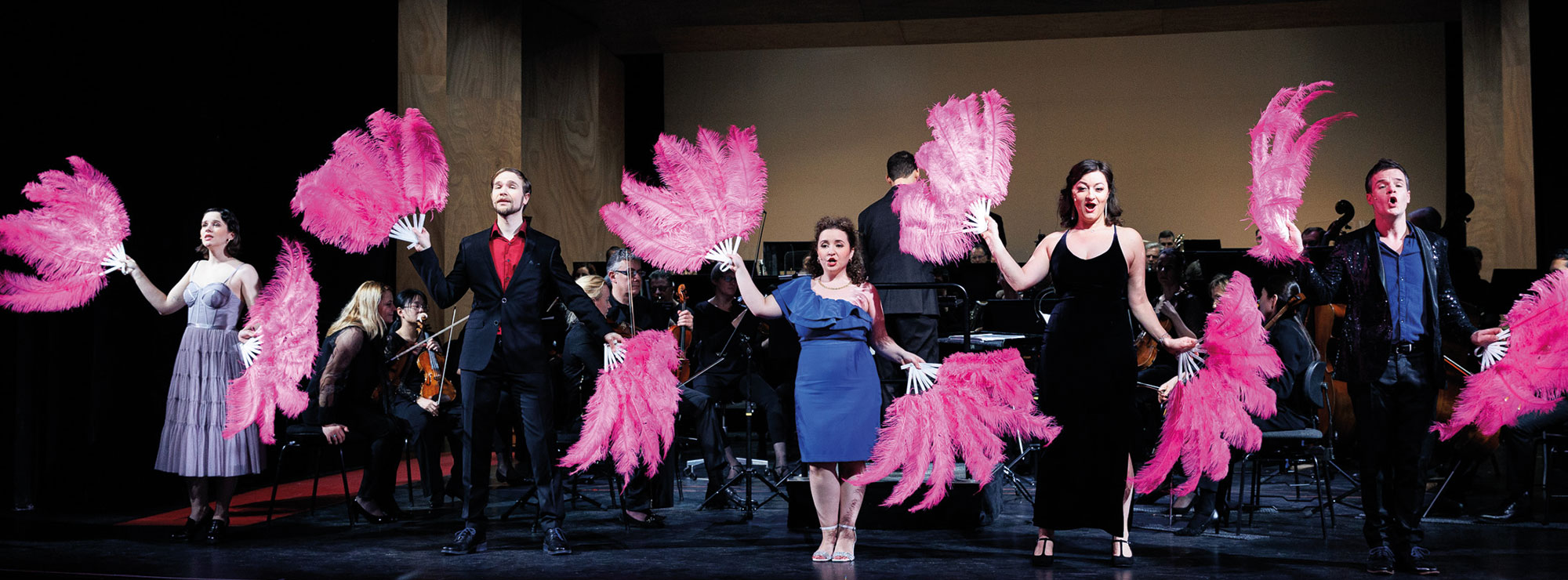 Die Solistinnen und Solisten der MUSICALGALA posieren mit großen pinken Fächern aus Federn